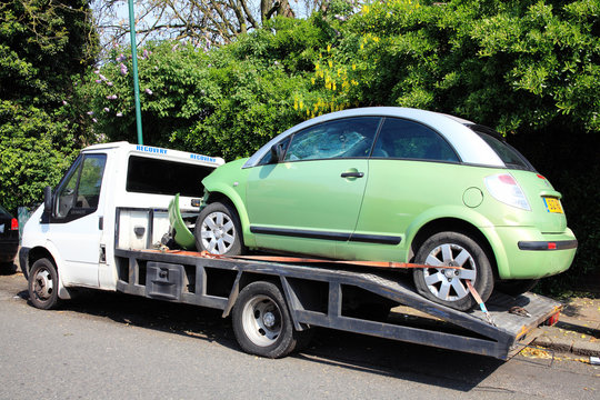 London, United Kingdom, April 21, 2014: A car automobile which has been damaged and wrecked by a crash accident loaded on a vehicle recovery transport truck stock photo image