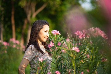 Beautiful Asian woman alone in the park with pink flowers