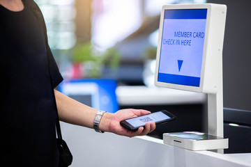 Selective focus to member card reader machine to check in with hand using smartphone to scan QR...