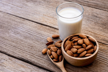 glass of milk with almonds on wood table.