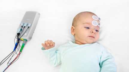 Newborn hearing screening and diagnosis at the hospital. Baby having hearing screening with special...
