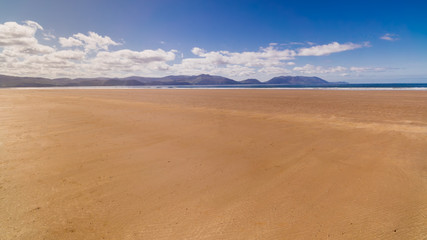 Fototapeta na wymiar Long, beautiful sandy Inch Beach with mountains in background. Summer day with blue sky on empty beach, relaxation. Dingle peninsula, Ireland