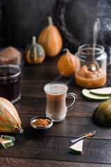 A cup with pumpkin latte on a wooden table. Still life with pumpkins. Hot drink.