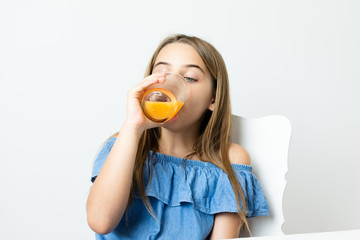 Criança menina bonita loira saboreando suco de laranja