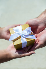 female hands accept a gift from male hands. on the street they give a box, a white bow. holiday concept, surprise