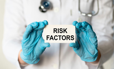 Doctor holding card in hands and pointing the word RISK FACTORS