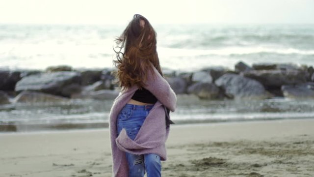Happy woman with long hair in front of the ocean rotating moving hair slow motion