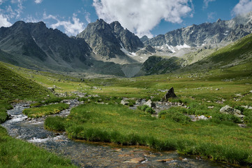 Fototapeta na wymiar Majestic mountains landscape with rocky ridge, green valley, river and cloudy sky.