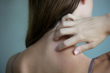 Close up view of woman scratching her neck.	