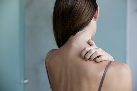 Close up view of woman scratching her neck.	