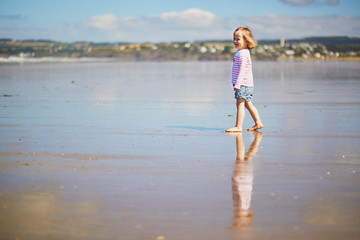 Adorable toddler girl on the sand beach at Atlantic coast of Brittany, France