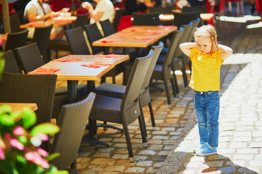 Unhappy and stubborn toddler girl in outdoor restaurant