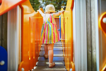 Adorable toddler girl having fun on playground