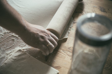 Preparing pizza dough. Young couple makes pizza for dinner. Romantic dinner. Cooking pizza at home. Rolling pin and flour on the table. Woman's and  man's hands together.