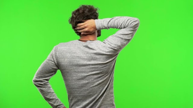 young man on chroma green screen from behind thinking about something