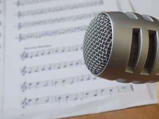 Micrófono en primer plano con fondo de partitura