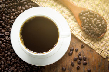 cup of coffee with beans on wooden table