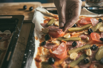 Woman cuts oliva on a cutting board. The stage of preparing pizza products. The lifestyle of a modern young family.