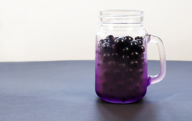Beautiful purple jar shaped mug full of ripe juicy fresh berries on a background of pastel colors