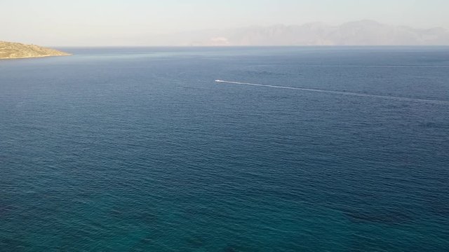 Aerial view of a jet ski boat in a deep blue colored sea. Spinalonga Island, Crete, Greece