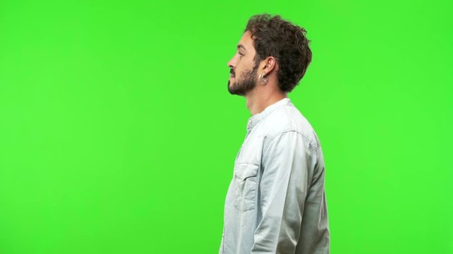 young man on chroma green screen on the side looking