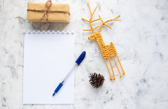 White notepad, spruce cone, vine deer and a gift on a light background. Flat lay, top view.