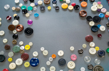 Many multi-colored buttons lie on the table, forming an empty space in the middle