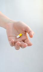 White-yellow pill in the form of a capsule lies in an outstretched female hand