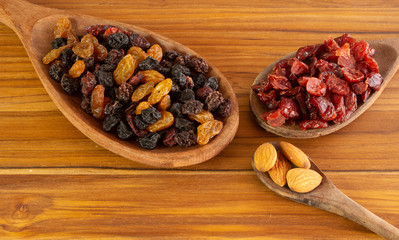 three spoons full of almonds, craberries and raisin