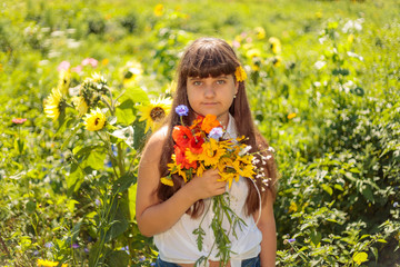 A young girl holding a summer flowers flower, bright green nature background