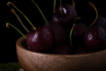 
Sweet cherries with water drops in a wooden cup close-up