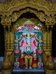 Lord Ganesha statue in standing posture with a decorated wooden background