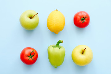 Various fresh vegetables and fruits on blue background. Shopping concept. Tomato, pepper, lemon, apple in row. Top view