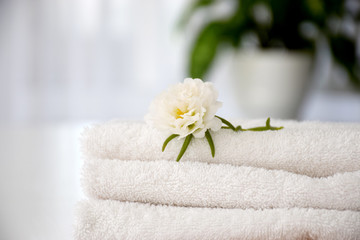 Fototapeta na wymiar Stack of white fresh towels with white flower. Laundry, washing or dry cleaning concept. Copy space.