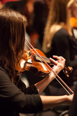 unrecognizable female brunette violinist playing in a professional orchestra. Shallow depth of...