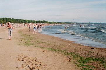 People chilling on the sandy beach in summer. Horizontal film photo.