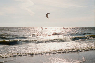 Kite surfers on the waves of Baltic Sea in Russia. Horizontal film photo.
