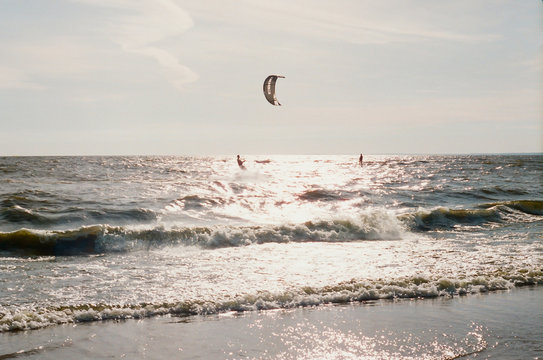 Kite surfers on the waves of Baltic Sea in Russia. Horizontal film photo.