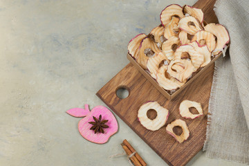 Organic apple chips on a wooden board. Cinnamon and anise on a light background. Healthy vegan vegetarian fruit snack. Natural food product