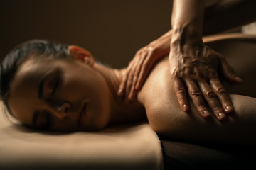 The beautiful girl has massage. Authentic image of luxury spa treatment. Warm colors, charming light.