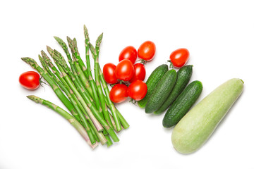 Fresh vegetables on a white isolated background. Asparagus, tomatoes, zucchini. Flat lay. The concept of proper nutrition.