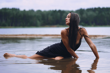 lying girl in a long black dress on the shore of the bay, the concept of the joy of health, sleep and relaxation             
