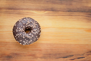 Chocolate-coated doughnut on a wooden Board, top view