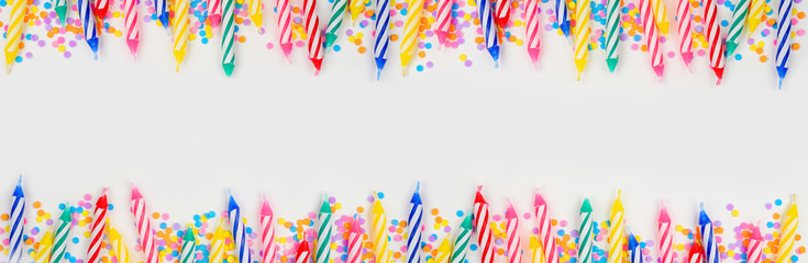 Colorful birthday cake candles with candy sprinkles. Top view banner with double border on a white background. Copy space.