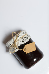 Jar of plum jam. With an inscription tag. On a white background.