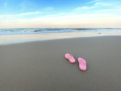 Summer holiday concept. Pair of pink sandals on the beach.