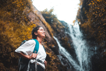 Young girl in white dress enjoying the beautiful waterfall view. Freedom and travel.