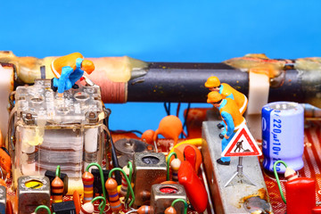 Miniature figure workmen inspecting a vintage radio circuit board radio repair concept