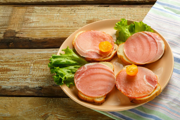 Sandwiches with ham and cherry on a wooden board on a napkin.
