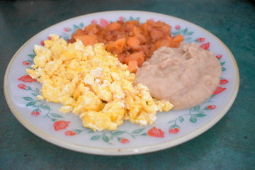 Un rico desayuno de papas con chorizo, huevos revueltos y frijoles